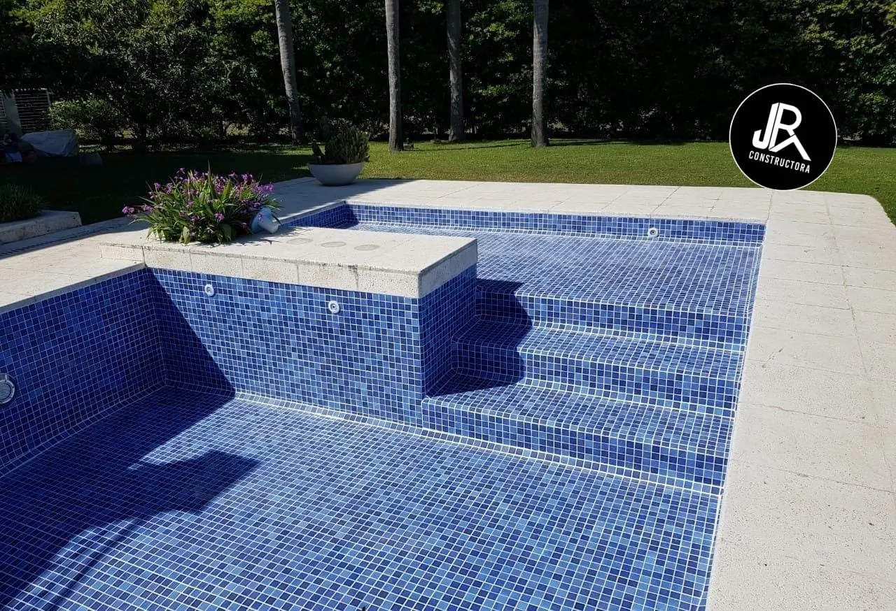 Piscina con mosaico azul y banco de obra